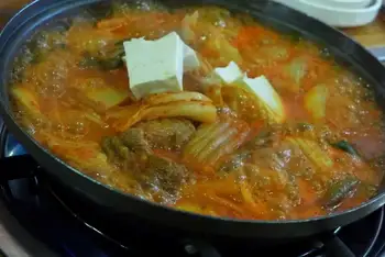 Scatter the green onions and serve bubbling, straight from the pot, with steamed rice.